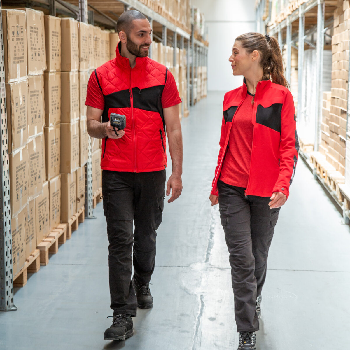 Foto van 2 medewerkers in een magazijn met werkkleding geschikt voor in de transport & logistiek
