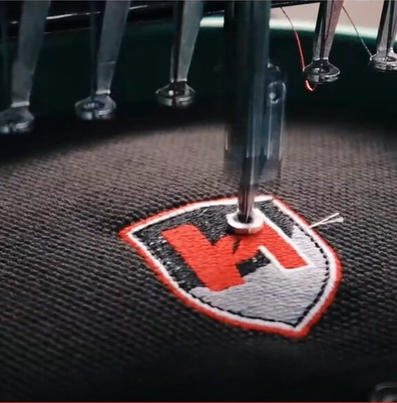 Foto van een borduring, voor dat wij beginnen krijg je een visuele presentatie om te garanderen dat je het juiste logo op de kleding hebt.